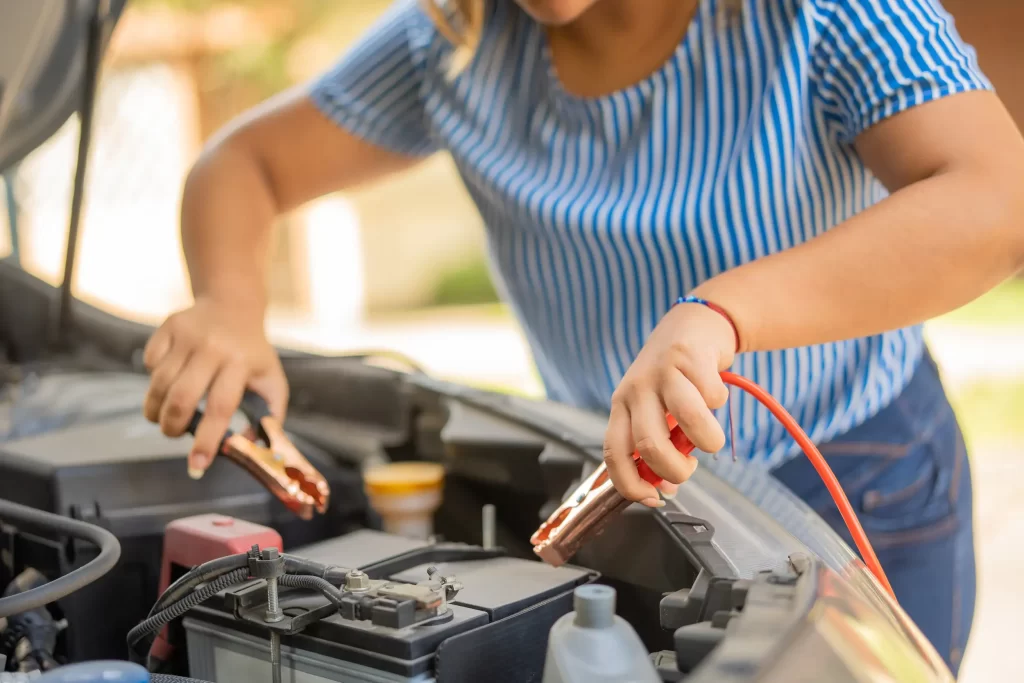 A woman attempting to jumpstart the battery of her broken car.