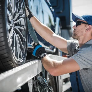 A tow truck driver tightening the rope for it won't fall at the back